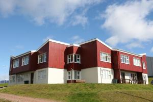 a red and white building on top of a hill at Framtid Hostel in Djúpivogur