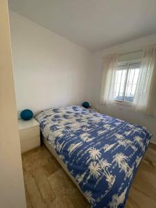 a bedroom with a bed with a blue and white comforter at Appartement Paraiso Riviera del Sol-Mijas in Málaga