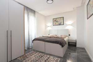 a white bedroom with a bed and a window at Deluxe Feliciano Apartments in Visoko