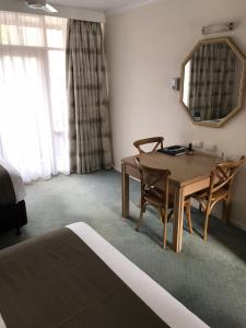 um quarto com uma mesa e cadeiras e um espelho em Moe Parklands Motel em Moe