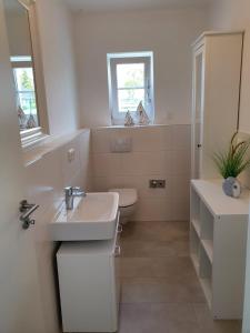 ein weißes Bad mit einem Waschbecken und einem WC in der Unterkunft Ferienhaus 2 Achterwasser-Findling Usedom in Lütow