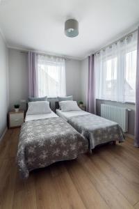 two beds in a bedroom with wooden floors and windows at Apartament Liliowa 4 z tarasem in Kudowa-Zdrój