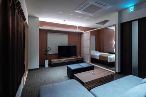 a hotel room with a television and a bed at Randor Residence Hiroshima Suites in Hiroshima