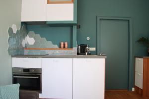 a kitchen with white cabinets and a blue wall at Bij Isa & Max in Kampen