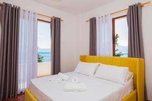 a bedroom with a yellow bed with a view of the ocean at Villa Gaudium in Vlorë