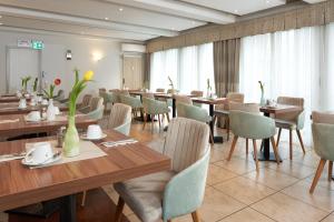 un restaurante con mesas de madera, sillas y flores en Hotel Meyerhof, en Lörrach
