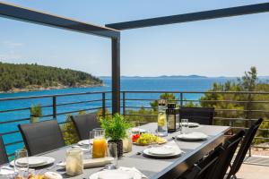 a dining table with a view of the ocean at WATERFRONT SEA DREAM VILLA in Milna