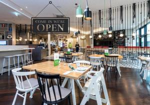 a restaurant with tables and chairs and a sign that reads come in write open at Holiday Inn Hamburg - City Nord, an IHG Hotel in Hamburg