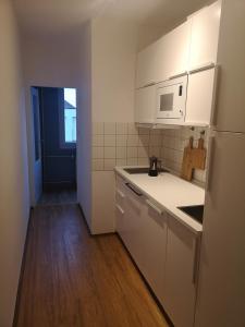 a small kitchen with white cabinets and a refrigerator at Apartmán Spa Šumava in Zdíkov +16 photos