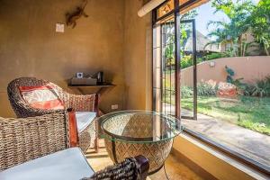 Zimmer mit einem Glastisch, Stühlen und einem Fenster in der Unterkunft AmaZulu Lodge in St Lucia