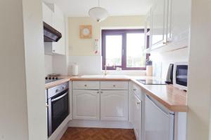 a white kitchen with white cabinets and a window at 3 Bed Cottage with Hot Tub & Near New Quay Wales in Llandysul