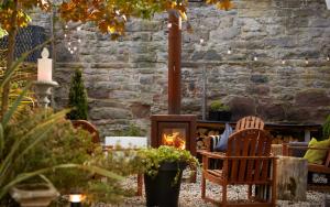 a patio with a fire place and chairs and a stone wall at 94DR in Edinburgh