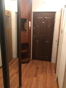 pasillo con puerta negra y suelo de madera en Apartament Szczecinek, en Szczecinek 1 foto más