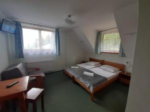 a bedroom with a bed and a desk and window at Domek HAWRAŃ in Jurgów