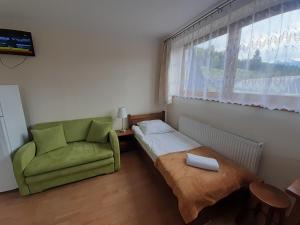 a room with a bed and a chair and a window at Domek HAWRAŃ in Jurgów