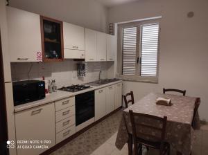 a kitchen with white cabinets and a table with chairs at Sweet Home Montecristo Civico 1 in Vibo Valentia