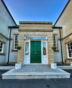 una porta verde su un edificio con due piante in vaso di Bailey's Court, Guest Accommodation a Portadown