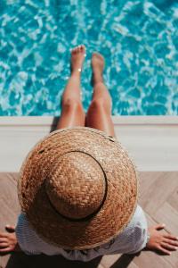 a person wearing a straw hat next to a swimming pool at Aiolos Suite in Sitia