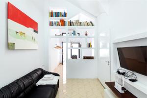 een woonkamer met een zwarte leren bank en een tv bij Aiolos Suite in Sitia