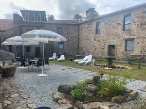 un patio con sombrilla, mesa y sillas en Albergue Ponte Olveira, en Mazaricos