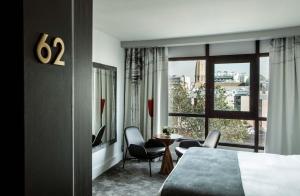 パリにあるル パリシス パリ トゥール エッフェルのベッドと椅子、窓が備わるホテルルームです。