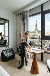 a woman sitting at a table with a view of the eiffel tower at Le Parisis - Paris Tour Eiffel in Paris +85 photos