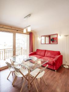 een woonkamer met een rode bank en een glazen tafel bij Chalets de Florence FORET & FAMILLE appartements by AlpVision Résidences in Valfréjus