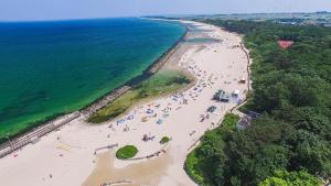 - une vue sur la plage avec des personnes dans l'eau dans l'établissement Diament Darłowo, à Darłowo