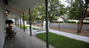a grassy area with a bench and a fence at Victorian Square Guesthouse in Graaff-Reinet