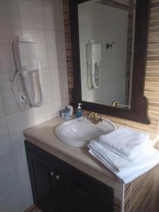 een badkamer met een wastafel, een spiegel en handdoeken bij STUDIOS CHRISTINA in Póroi
