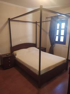 een slaapkamer met een hemelbed en een raam bij STUDIOS CHRISTINA in Póroi