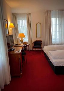 a hotel room with a bed and a desk with a computer at Hotel Daniels in Hallbergmoos