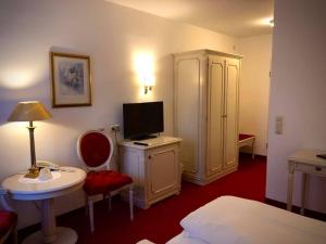 Habitación de hotel con cama y escritorio con TV. en Hotel Daniels en Hallbergmoos