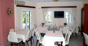 a dining room with white tables and white chairs at Venardos Hotel in Agia Pelagia Kythira