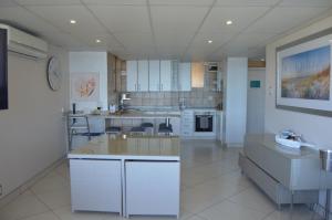 a large kitchen with white cabinets and a large island at Accommodation Front - Classy 4 Sleeper with Ocean Views in Durban