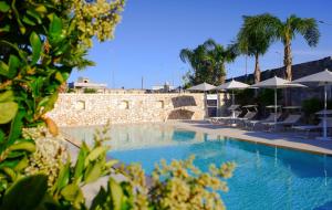 - une piscine avec des chaises et des parasols à côté d'un mur dans l'établissement Villa Rosa Antico Dimora Storica, à Otrante