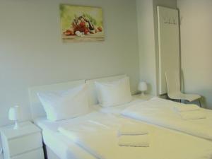 - un lit blanc avec des oreillers blancs et une photo sur le mur dans l'établissement BNB Potsdamer Platz - Rooms & Apartments, à Berlin