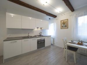cocina con armarios blancos, mesa y fregadero en Residence SS Giovanni e Paolo, en Venecia