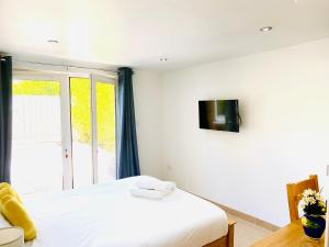 - une chambre avec un lit et une télévision murale dans l'établissement Amber Lodge Hickstead-C, à Haywards Heath