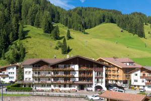a hotel in the mountains with a green hill at Hotel Genziana in Selva di Val Gardena