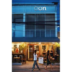 two people walking in front of a restaurant at Oon Poshtel x Cafe in Chiang Mai
