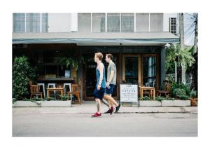two men walking down a street in front of a store at Oon Poshtel x Cafe in Chiang Mai