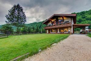a large house with a grassy field in front of it at Avalanche Plaiul Foii in Zărneşti