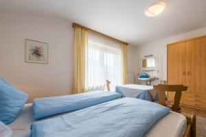 a bedroom with a bed and a table and a window at Almliesl HOLL-453 in Hollersbach im Pinzgau