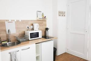 a kitchen with a sink and a microwave at #4 Joli appartement à 2 pas du Métro et Paris 20 in Bagnolet +4 photos