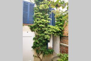 a building with blue shutters and a white door at #4 Joli appartement à 2 pas du Métro et Paris 20 in Bagnolet