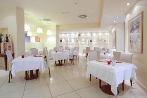 a dining room with white tables and white chairs at Hotel Touring in Fiorano Modenese