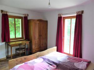 a bedroom with a bed with red curtains and a desk at Hiša ob potoku in Avče