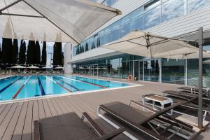 a swimming pool with chairs and umbrellas next to a building at Спорт инн отель и спа in Adler