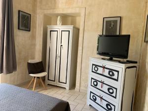 a bedroom with a tv and a dresser with a television on it at Le château des Anglades in Hyères